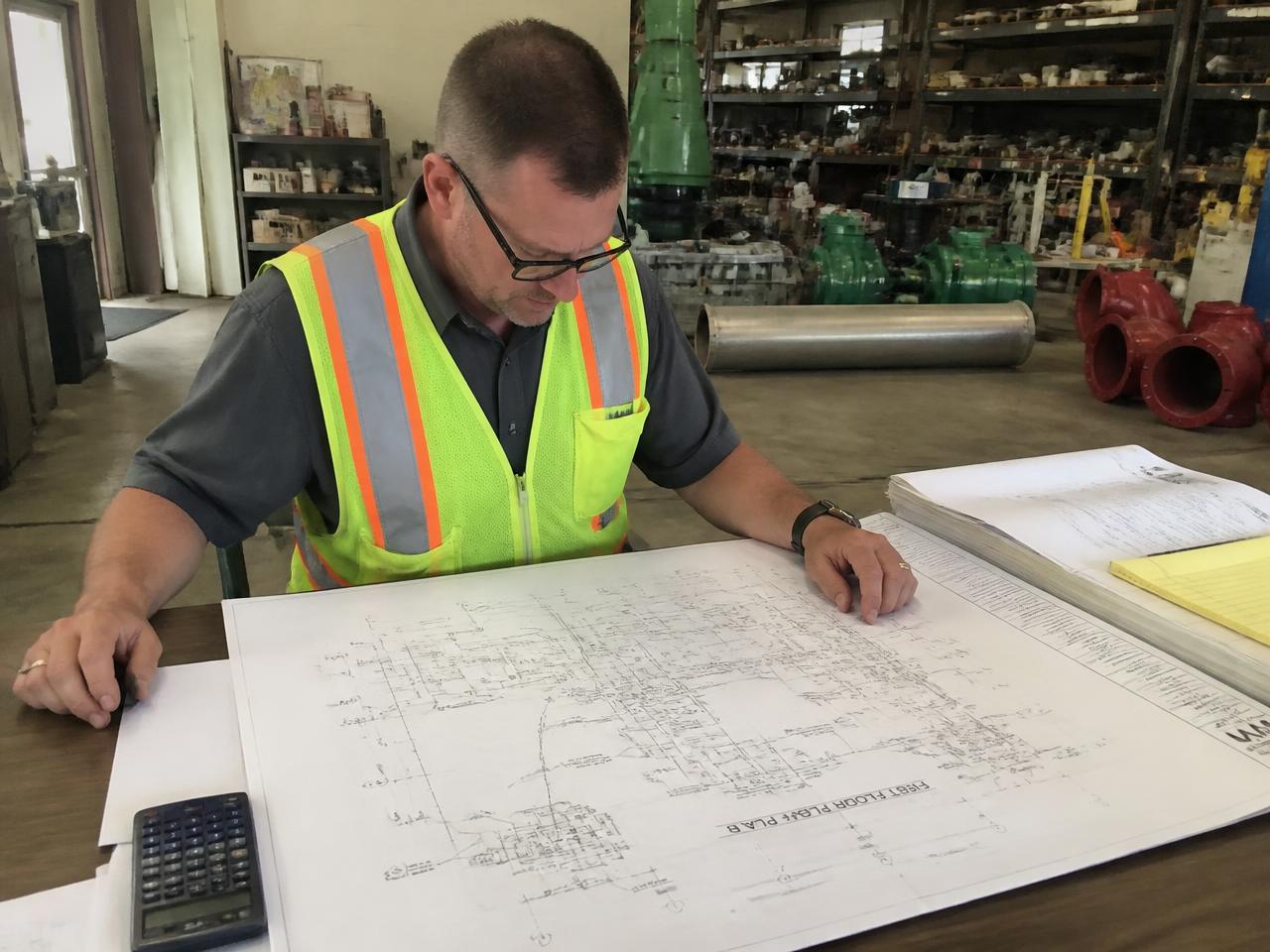 An estimator reviewing large mechanical drawings in a contractor’s shop